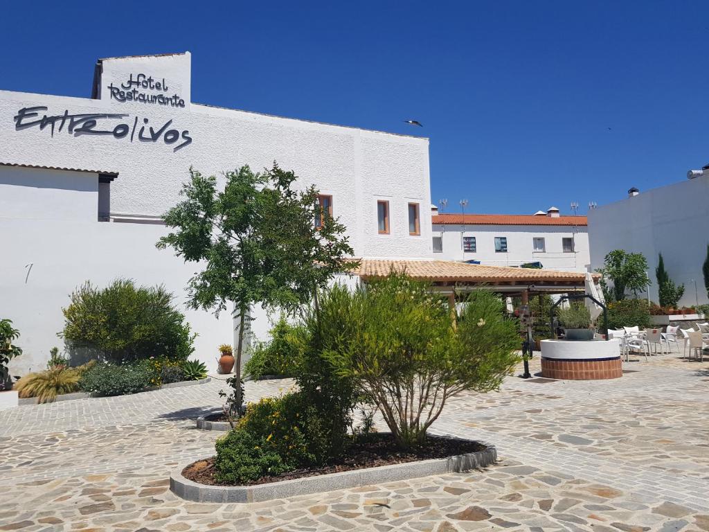 a white building with a tree in a courtyard at Hotel Entreolivos in El Pedroso