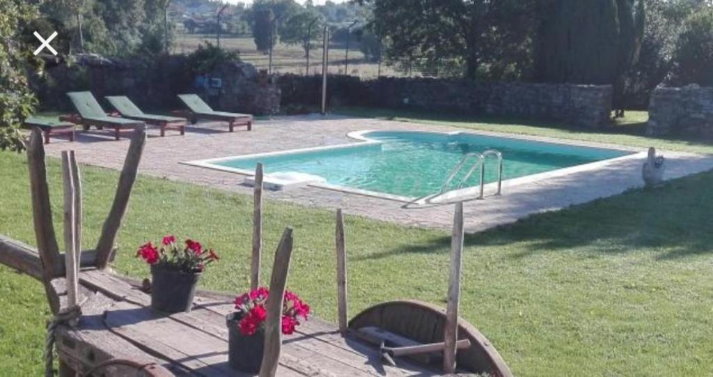 a swimming pool with a bunch of chairs in a yard at Casa rural osvilares in Santiago de Compostela