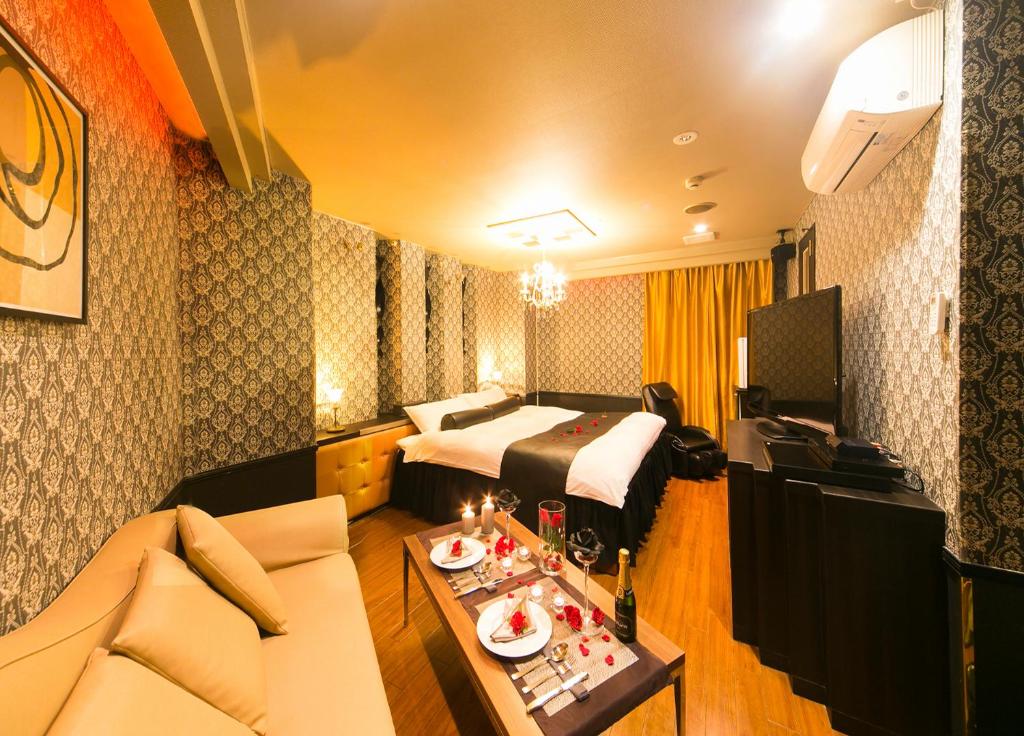仙台市にあるHotel Renaissance Sendai -Adult Onlyのベッドとソファ付きのホテルルーム