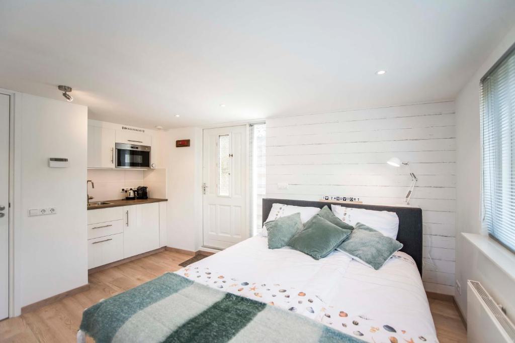 een witte slaapkamer met een bed en een keuken bij Studio 4 U in Zandvoort