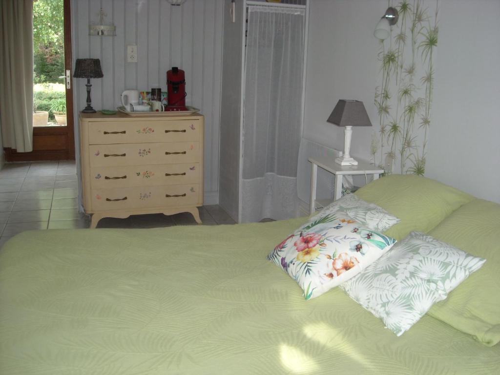 een slaapkamer met een groen bed met 2 kussens en een dressoir bij Côté Sud in Sarlat-la-Canéda