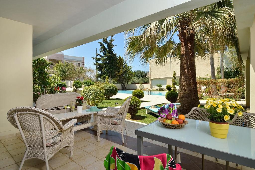 patio ze stołami i krzesłami oraz palmą w obiekcie Alexandra's Relaxing Suite w mieście Kalamaki