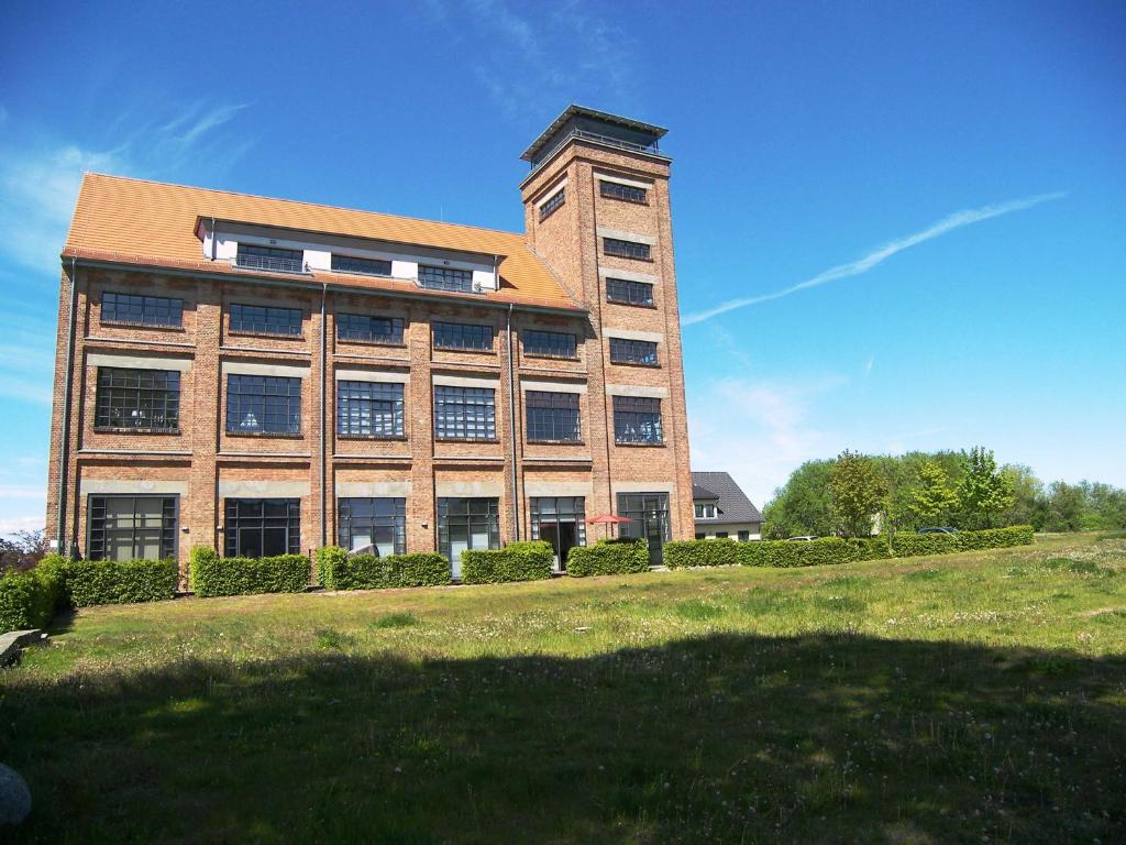 ein großes Backsteingebäude mit einem Feld davor in der Unterkunft Loft de Mar -Schlossinsel- in Wolgast