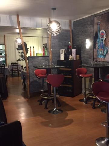 un salon de coiffure avec tabourets rouges dans une pièce dans l'établissement Hôtel La Tour D'Auvergne, à Pont-lʼAbbé