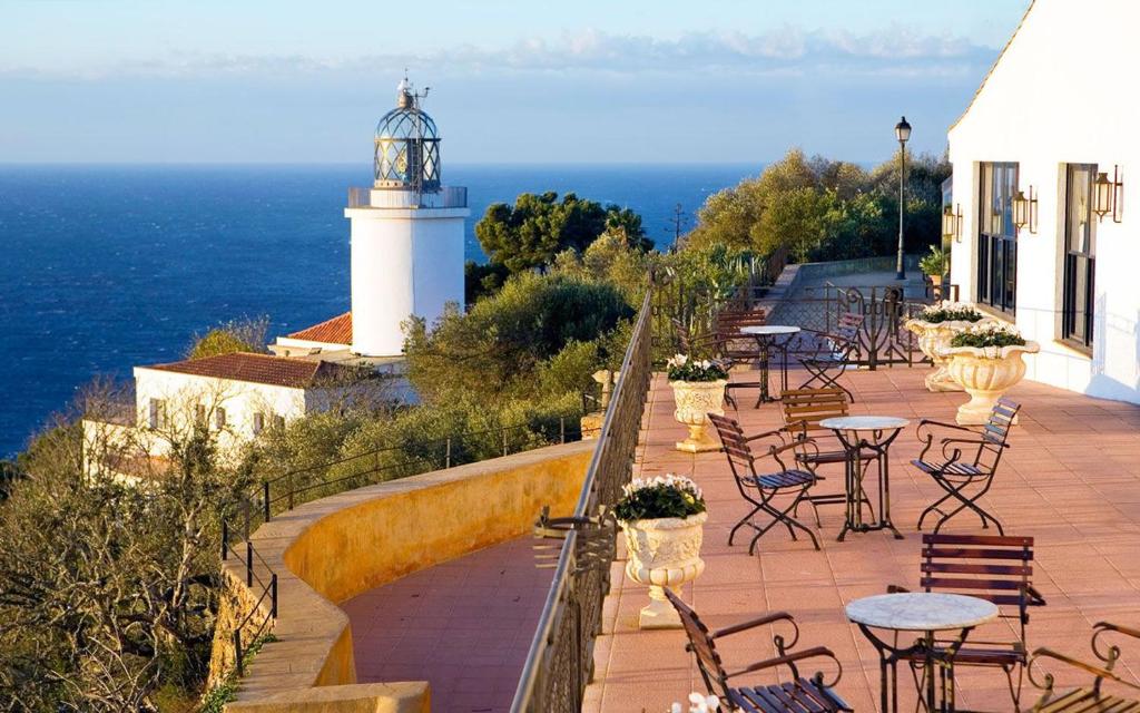a lighthouse sitting on top of a patio with tables and chairs at El Far Hotel Restaurant in Llafranc