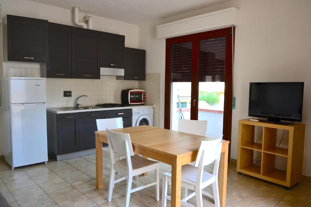 una cucina con tavolo in legno ed elettrodomestici bianchi di Appartamento Arcobaleno a Marina di Bibbona