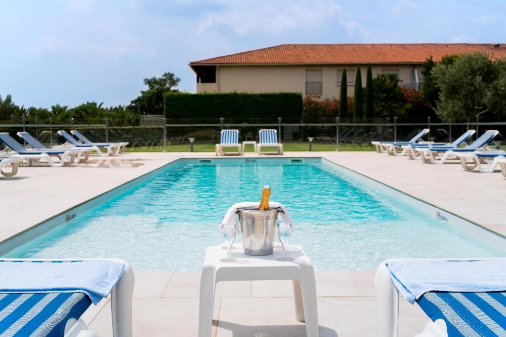una piscina con sillas y un exprimidor en una mesa junto a una piscina en Hôtel Ariane, en Fos-sur-Mer