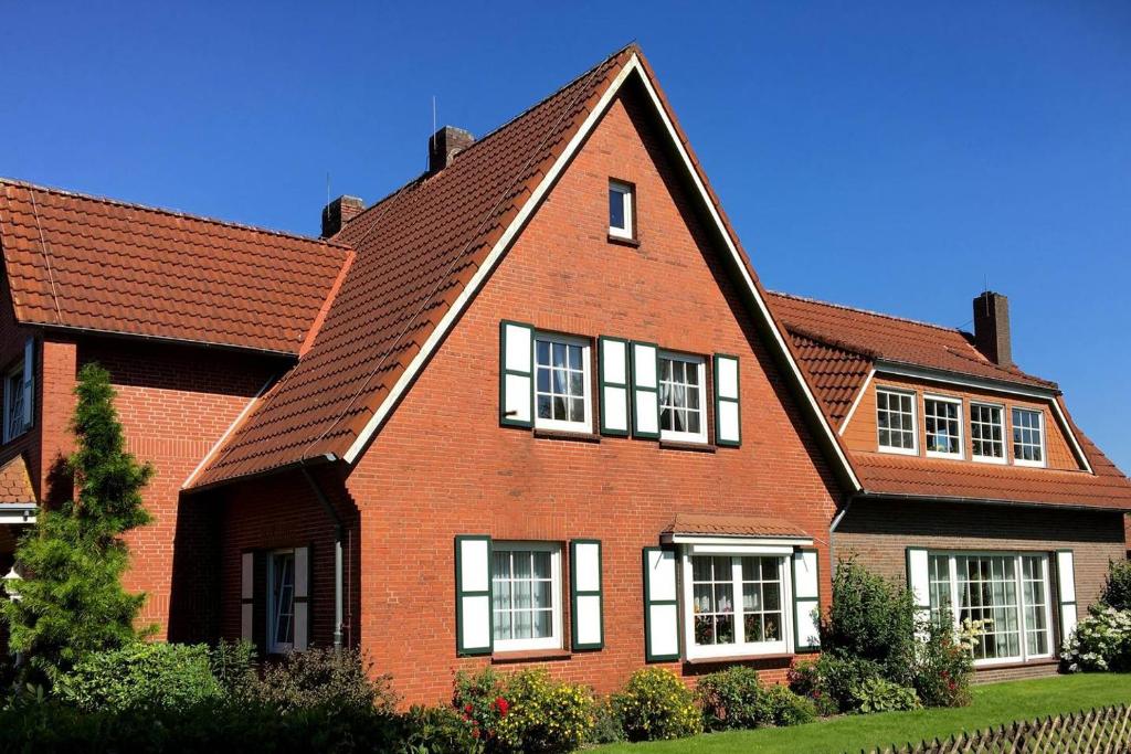 uma grande casa de tijolos vermelhos com telhado castanho em Ruhige Unterkunft nahe der Nordsee em Friedeburg