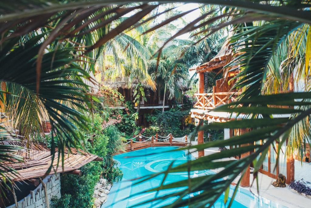 a pool in a resort with a palm tree at Casa Las Tortugas Petit Beach Hotel & Spa in Holbox Island