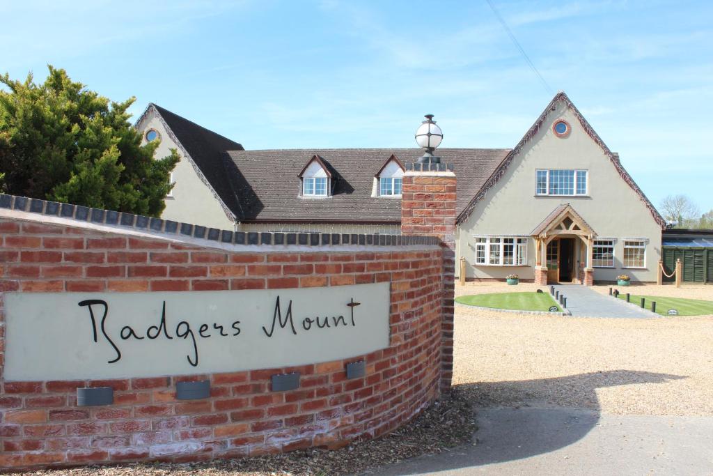 a brick wall with a sign in front of a house at Badgers Mount Hotel in Earl Shilton