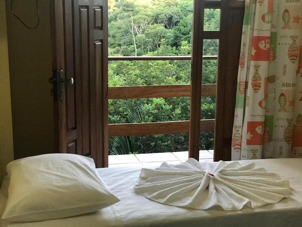 a bed with a bow on it in front of a window at Pousada Sereia Dourada in Itacaré