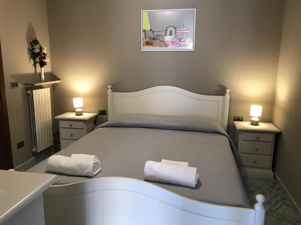 1 dormitorio con 1 cama blanca y 2 toallas en Anfite Apartments Castelletto, en Peschiera del Garda