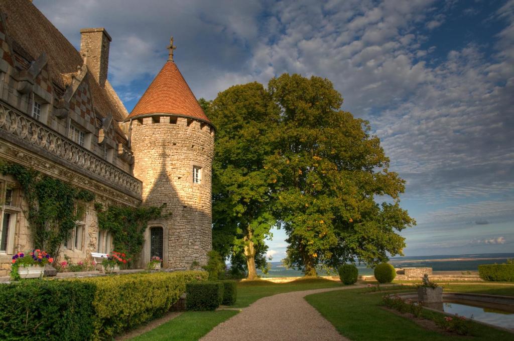 ein Gebäude mit einem Turm und einem Baum daneben. in der Unterkunft Hattonchatel Château & Restaurant La Table du Château in Hattonchâtel