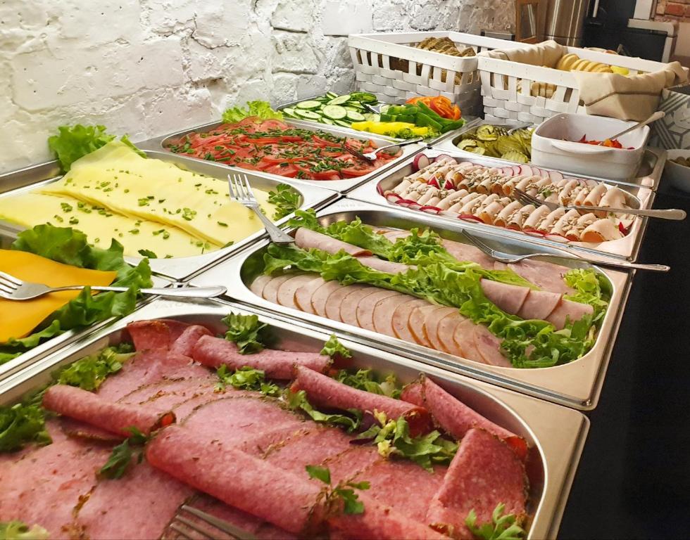 ポズナンにあるExpolis Residence - City Center MTP TARGI- Reception 24hの様々な種類の肉や野菜を取り揃えたビュッフェ
