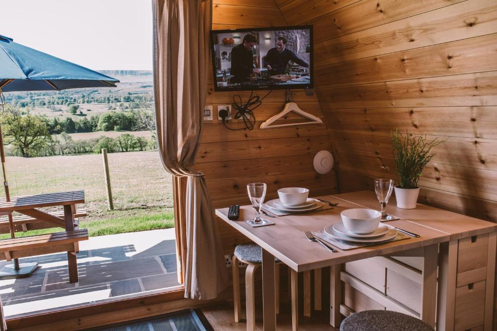 a dining room with a table and a television in a cabin at Wensleydale Glamping Pods in Redmire