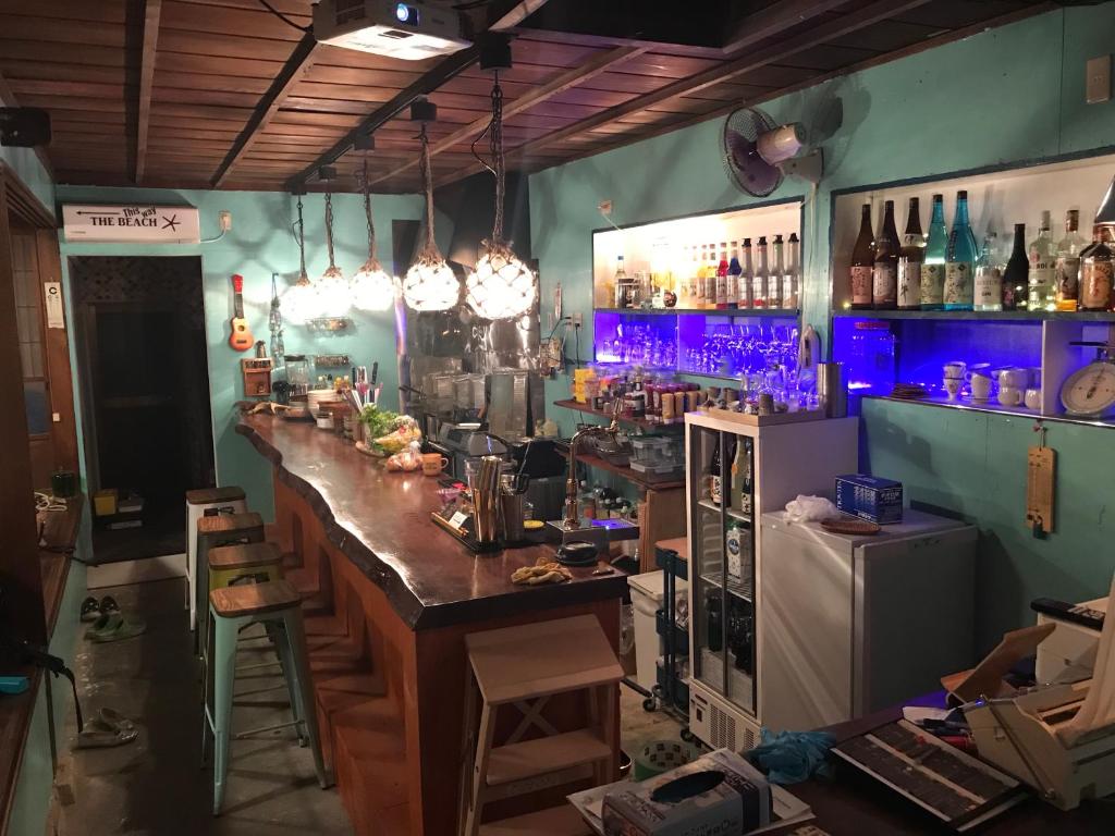 un bar con barra en una habitación con botellas en Guest house & Bar Diamond Head, en Mihana