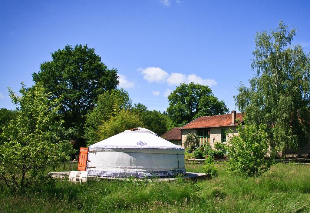 a yurt in a field in front of a house at Yourtes de Vassivière in Peyrat-le-Château