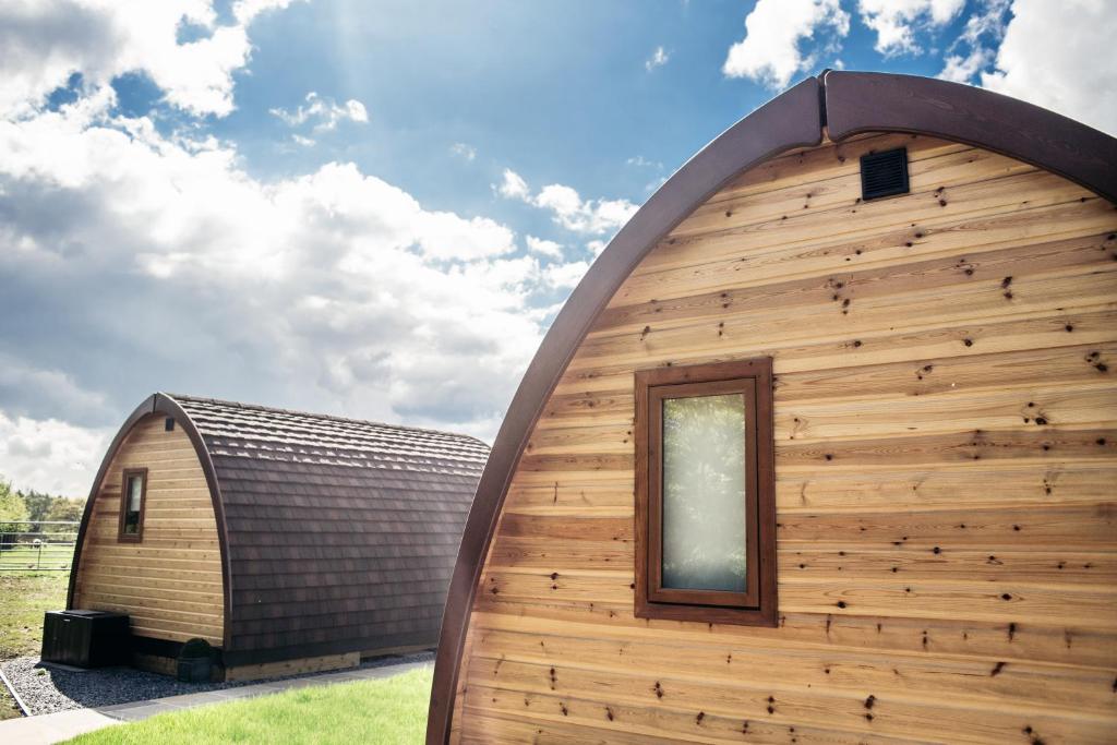 a large wooden building with a gambrel roof at Wensleydale Glamping Pods in Redmire