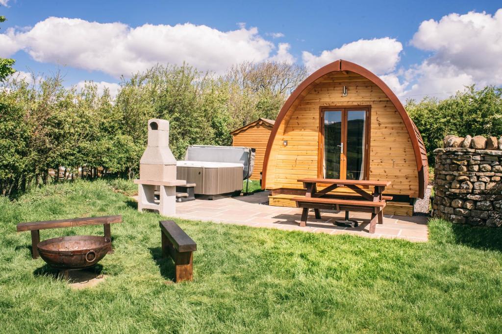 a small wooden cabin with a picnic table and benches at Wensleydale Glamping Pods in Redmire