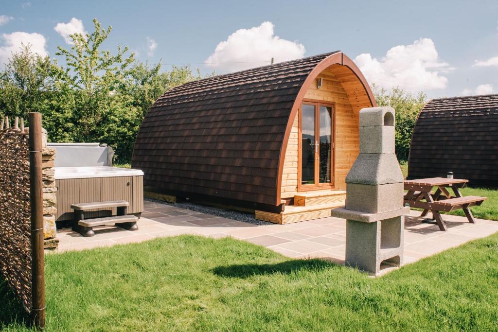 a small wooden hut with a table and a bench at Wensleydale Glamping Pods in Redmire