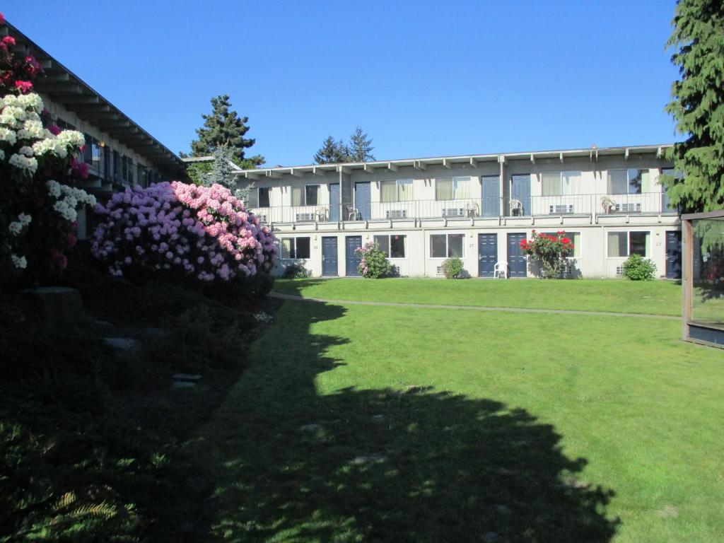 a building with flowers in front of a yard at Cocusa Motel in Burlington