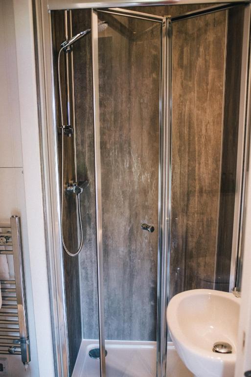 a shower with a glass door next to a sink at Wensleydale Glamping Pods in Redmire