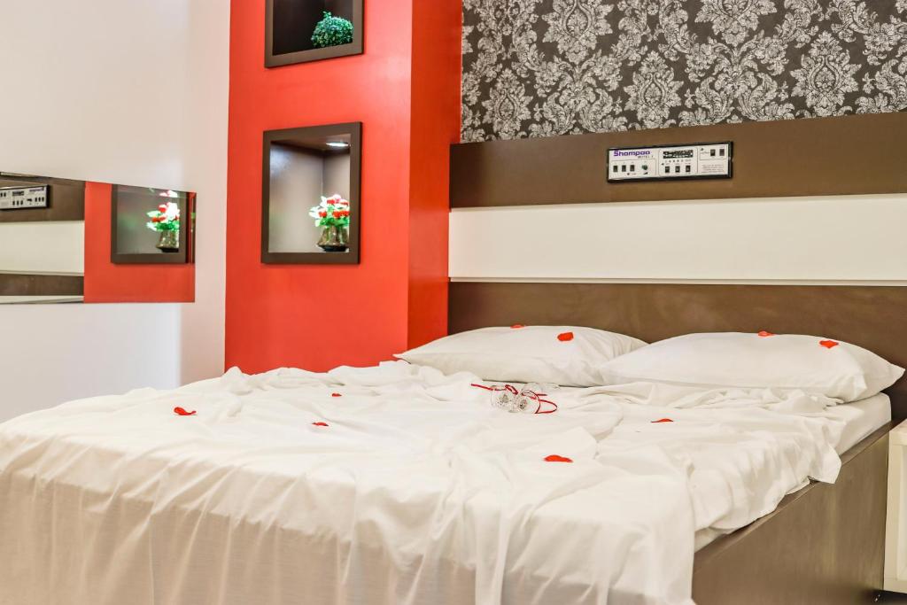 um quarto com uma cama branca e uma parede vermelha em MOTEL SHAMPOO (Adult Only) em Brusque