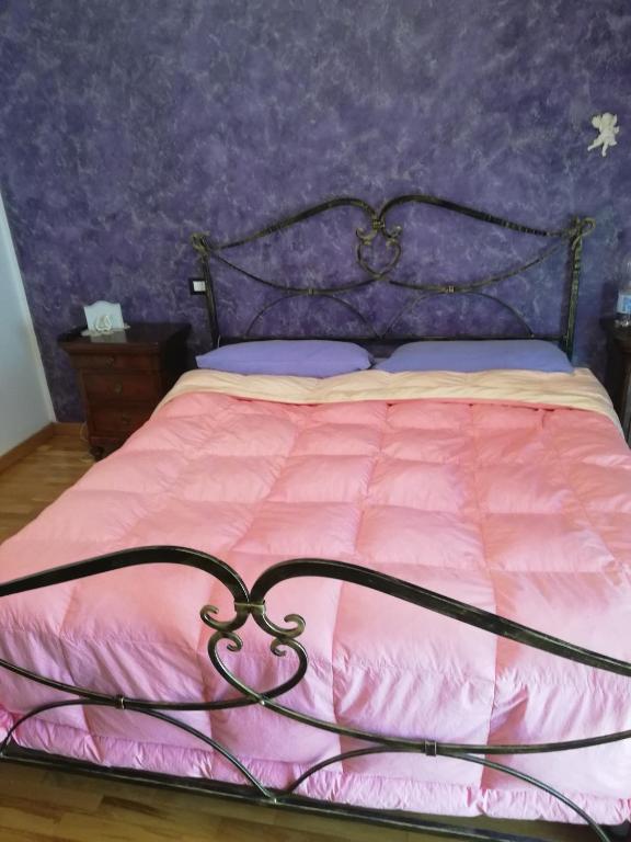 una camera con letto rosa e parete viola di La Casa di Lucia a L'Aquila