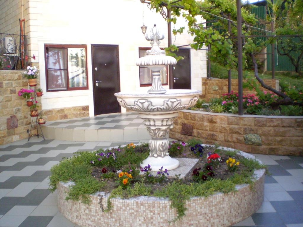 a fountain in the middle of a courtyard with flowers at Гостевой дом Барс Абхазия in Tsandrypsh