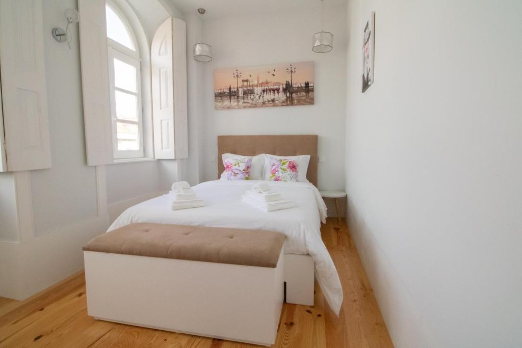 - une chambre avec un lit blanc et un pouf blanc dans l'établissement Passeio da Avenida - Central Avenue Apartment with Elevator, à Viana do Castelo