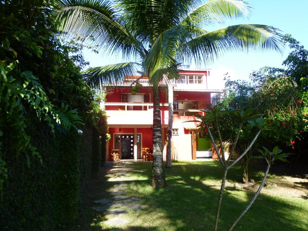 a red house with a palm tree in front of it at Pousada Halai in Morro de São Paulo