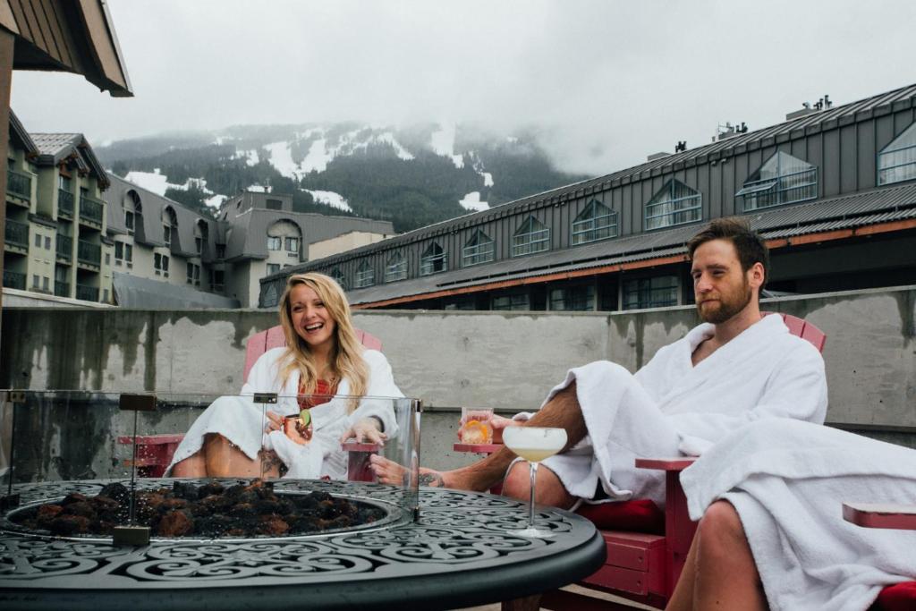 a man and a woman sitting around a table at Adara Hotel in Whistler