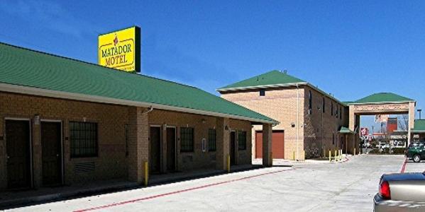 a building with a yellow sign on top of it at Matador Motel in San Antonio
