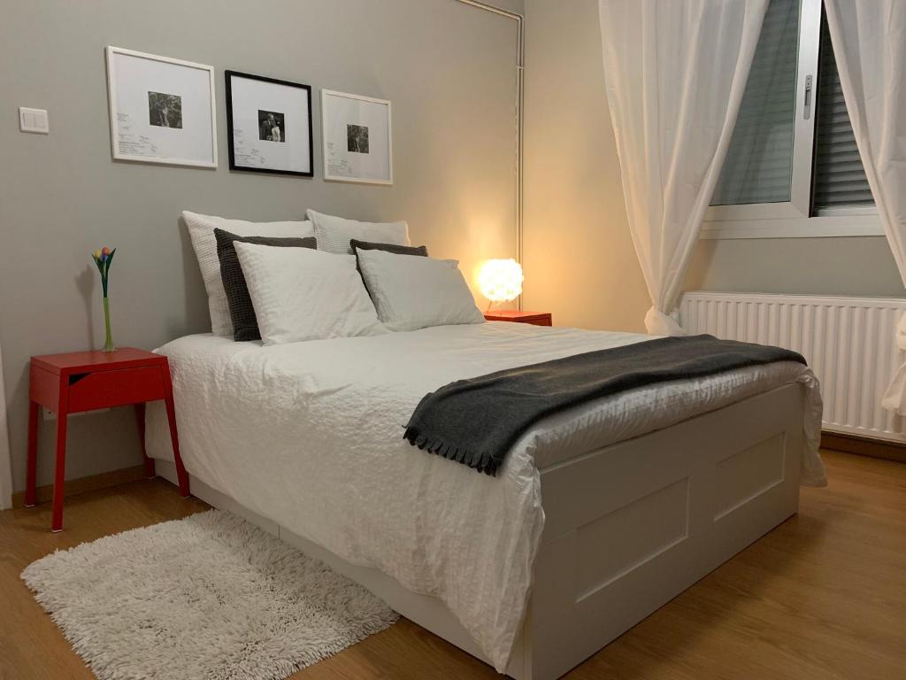 a bedroom with a white bed with a red side table at Strovolos Value Suites in Strovolos