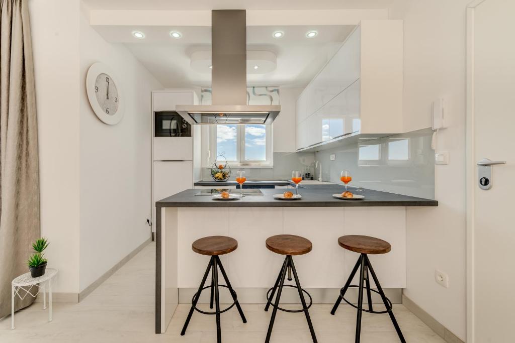 uma cozinha com uma ilha com dois bancos de bar em Modern 4* luxury apartment in center em Trogir