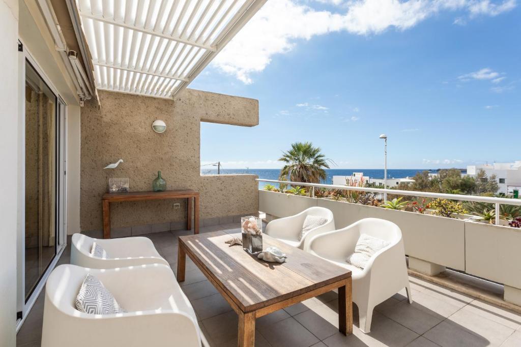 balcón con mesa de madera y sillas blancas en PillowAbroad - Poris Vista Mar, en Porís de Abona