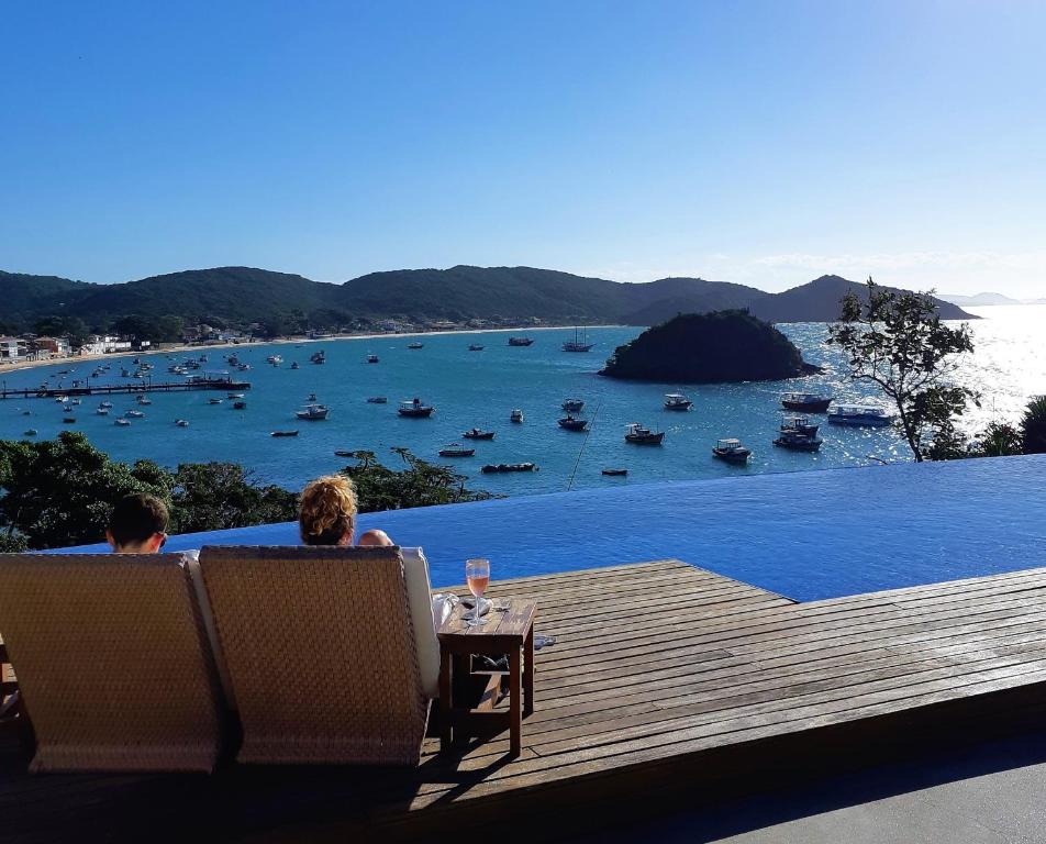 dos personas sentadas en sillas en una terraza mirando el agua en Abracadabra Pousada, en Búzios