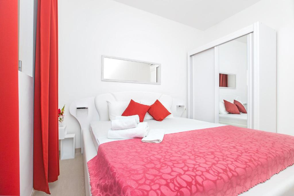 a white bedroom with a large bed with red pillows at Apartments Castello in Kotor