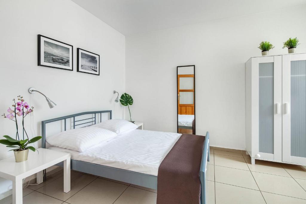 a white bedroom with a bed and a table at Sleepy3city Apartments Abrahama 16 in Gdynia