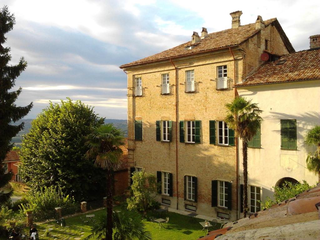 an old building with a palm tree in front of it at Albergo Real Castello in Verduno