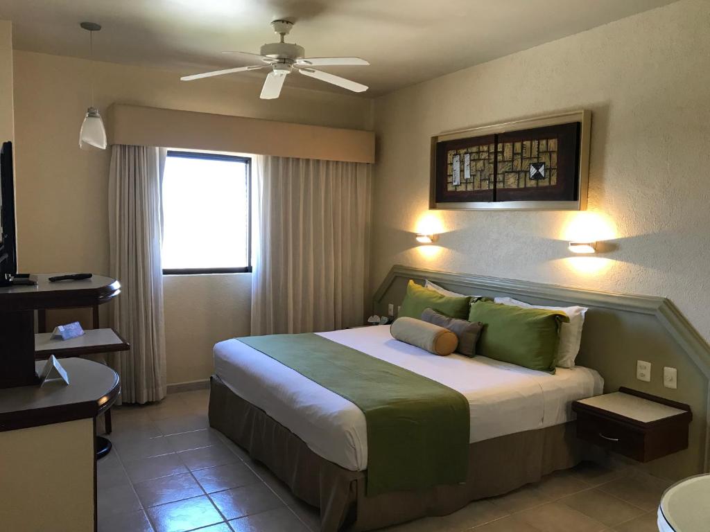 Olas Altas Inn Hotel & Spa في مازاتلان: غرفة نوم بسرير ومروحة سقف
