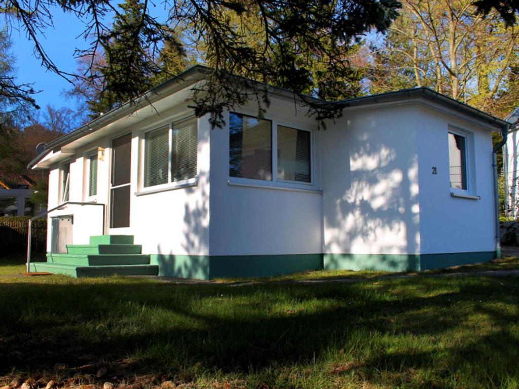 een wit huis met groene rand op een gazon bij Ferienhaus Sonnensteg in Ostseebad Sellin