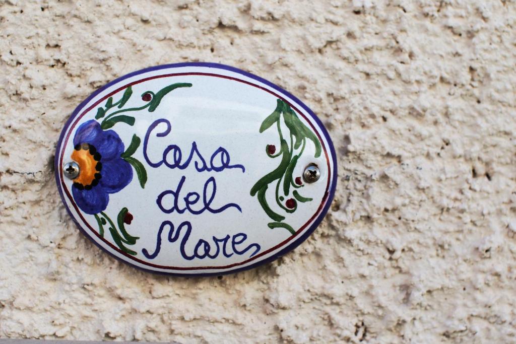 une plaque avec une fleur sur un mur dans l'établissement Casa del mare, à Capitolo