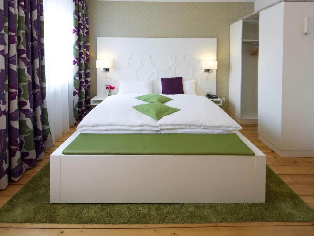 a bedroom with a white bed with a green rug at Hotel Karolinger Hof in Lorsch