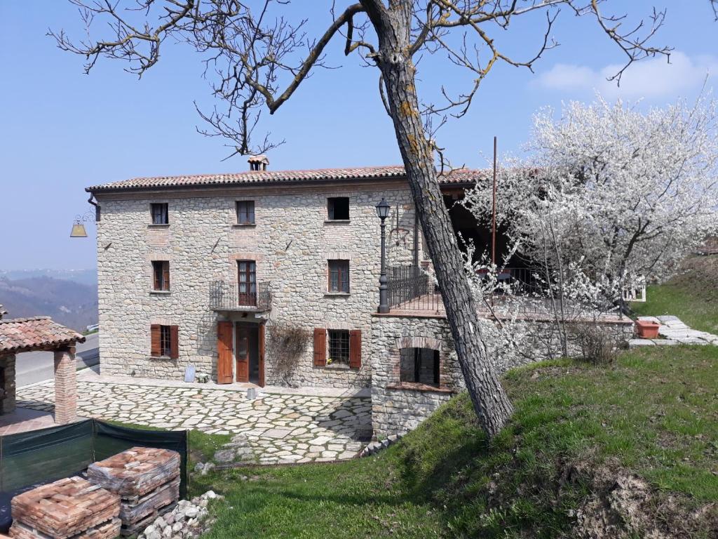 una vieja casa de piedra en una colina con un árbol en Ca' Növa, en Valverde Pavia