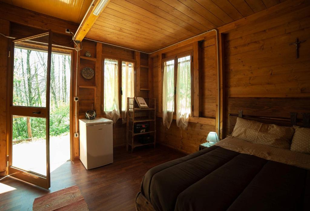 a bedroom with a bed in a wooden cabin at CHALET NEL BOSCO - TENUTA BOCCHINERI in Rogliano