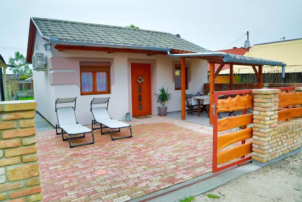 a house with two chairs on a brick patio at Jázmin Apartman in Buzsák