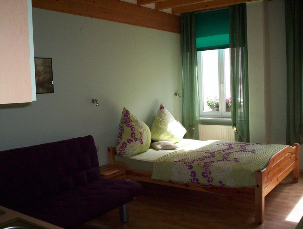 a bedroom with a bed and a chair and a window at Zum Belzenikel in Dernbach