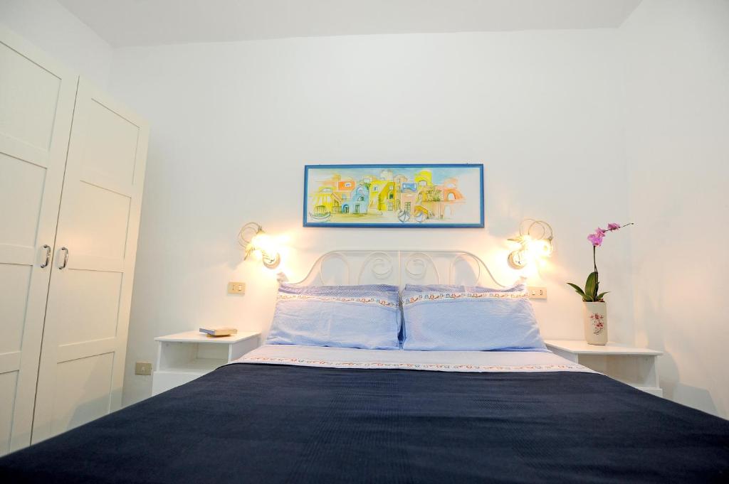 a bedroom with a bed with blue sheets and two lights at Le Querce in Procida