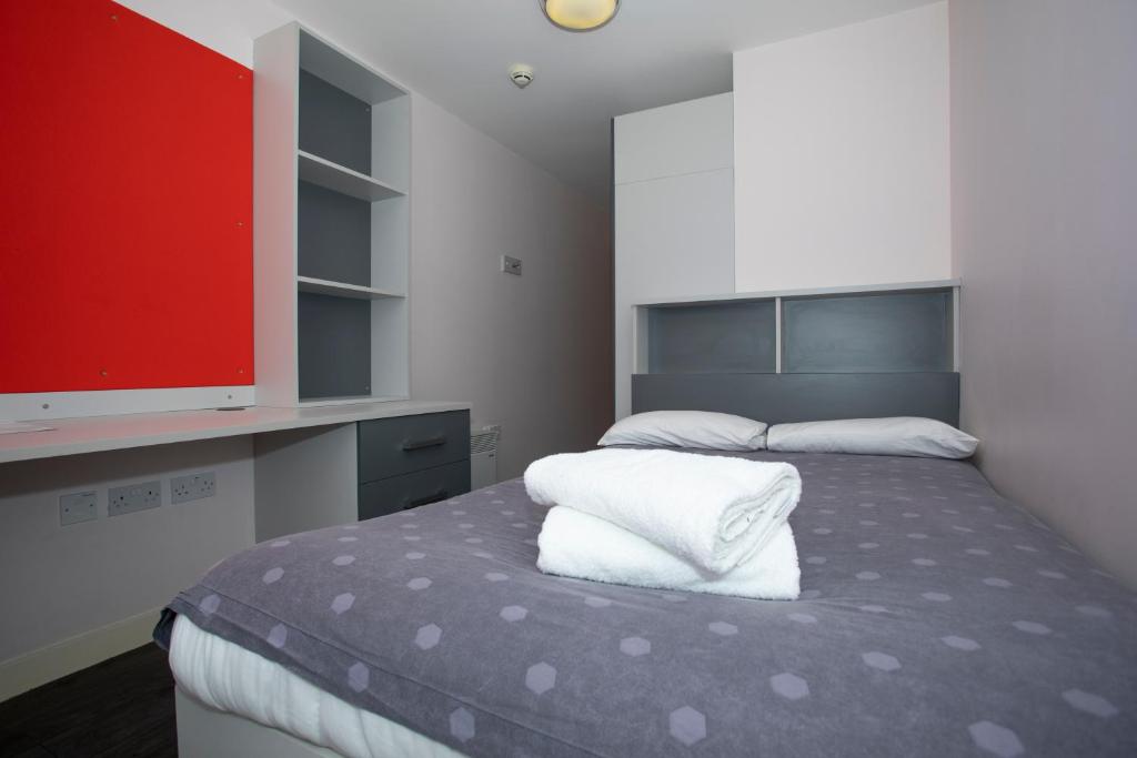 een slaapkamer met een bed met 2 kussens en een televisie bij Beaverbank Place - Campus Residence in Edinburgh